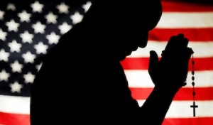 PHOTO ILLUSTRATION OF MAN HOLDING ROSARY WITH U.S. FLAG IN BACKGROUND